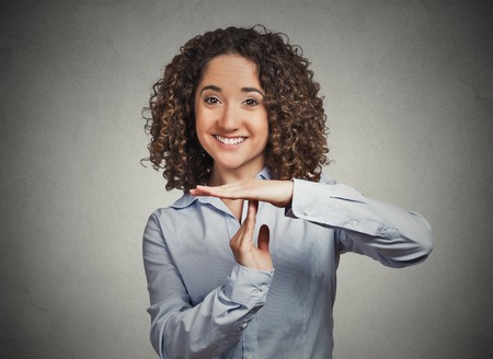 Closeup portrait young happy, smiling woman showing time out gesture with hands, isolated grey wall background. Positive human emotions, facial expressions, feelings, body language, reaction, attitudeの写真素材