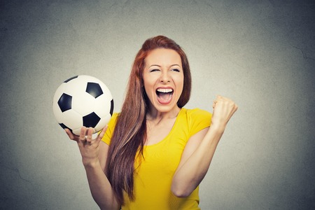 Portrait excited woman screaming celebrating team success holding football