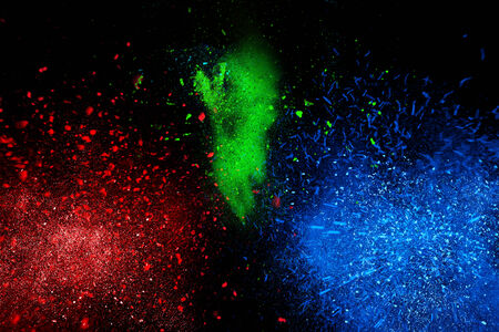 Freeze motion of colorful powder exploding, isolated on black, dark background. Abstract design of dust cloud. Particles explosion, screen saver wallpaper with copy space. Vivid yellow green red ashの写真素材