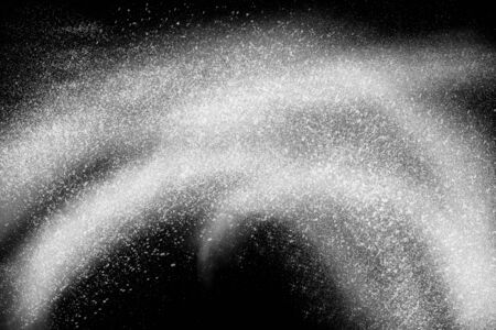 Freeze motion of white powder exploding, isolated on black, dark background. Abstract design of white dust cloud. Particles explosion screen saver, wallpaper with copy space. Planet creation conceptの写真素材
