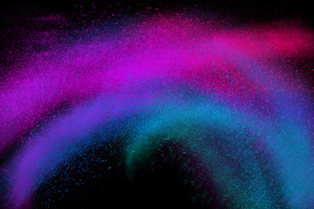 Freeze motion of colorful powder exploding, isolated on black, dark background. Abstract design of dust cloud. Particles explosion screen saver wallpaper with copy space. Vivid blue magenta violet ashの写真素材