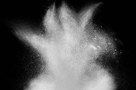 Freeze motion of white powder exploding, isolated on black, dark background. Abstract design of white dust cloud. Particles explosion screen saver, wallpaper with copy space. Planet creation conceptの写真素材