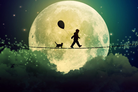 Happy boy teenager and cat walking with balloon on a tight rope above clouds with moonlight moon...