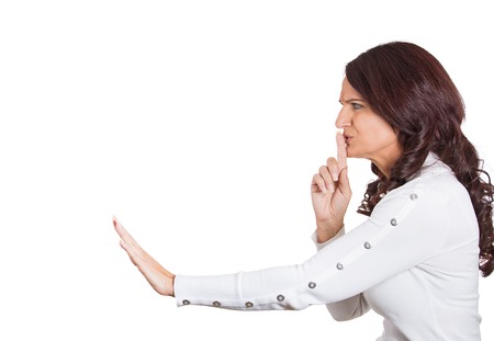 Side profile serious woman placing finger on lips pointing at someone, shhhhh, quiet, silence