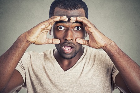 Portrait shocked young man isolated on gray wall backgroundの写真素材