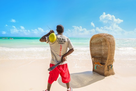 Where there is a coconut tree there is long life. Young man with fresh coconut and machete  enjoying ocean view in tropical paradiseの写真素材
