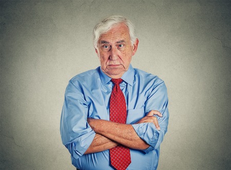 Portrait of unhappy grumpy pissed off senior mature man isolated on gray wall background. Negative human emotions, face expression feelingsの写真素材