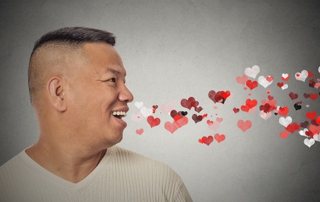 Side view portrait man sending kisses, red hearts coming out of open mouth, isolated grey wall background. Positive emotions, facial expression. Valentines dayの写真素材