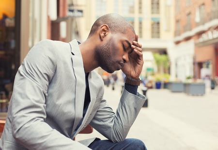Portrait stressed young man hands on head with bad headache isolated city street background. Negative human emotion facial expression feelingの写真素材