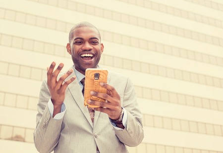 Excited man looking at his smart phone reading good news message emailの写真素材