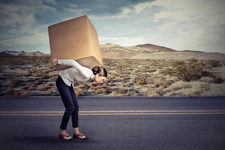 Woman carrying on her shoulders a large boxの写真素材