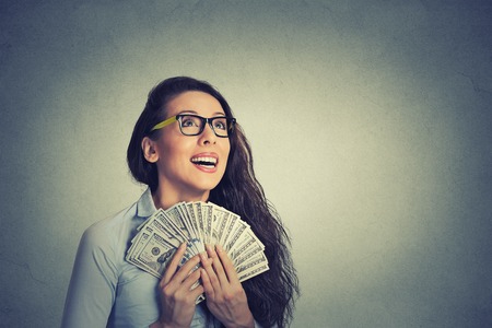 Closeup portrait happy excited successful young business woman holding money dollar bills in hand...