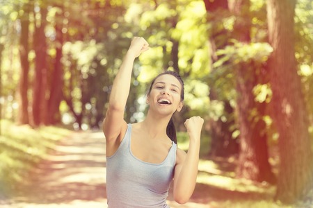 Portrait fit female fitness runner joyful and excited after running. Woman pumping fists. Success in sport training wellness concept. Positive face expression emotionの写真素材
