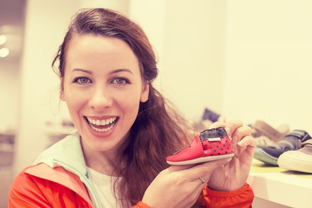 Closeup portrait happy excited young woman buying shoes for her child in retail store. Positive face expression emotion feelingsの写真素材