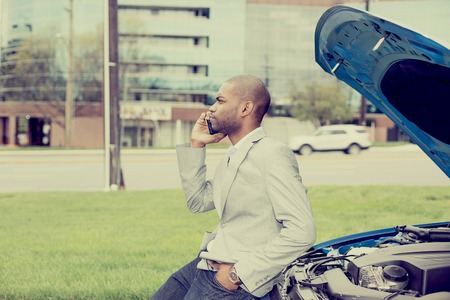 young man having trouble with his broken car calling for help on cell phone isolated on city road...