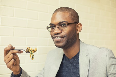 Young handsome man eating mixed vegetable meal in cafe chain restaurantの写真素材