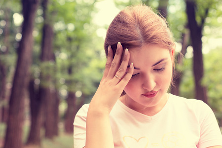 portrait stressed sad young woman standing outdoors on summer day in parkの写真素材