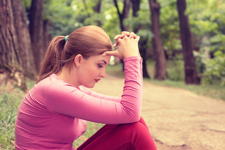 portrait stressed sad young woman sitting outdoors on summer day in parkの写真素材