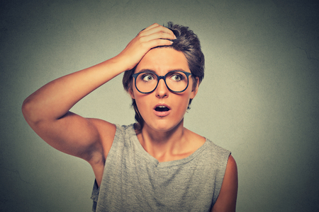Surprise astonished woman. Closeup portrait woman with glasses looking surprised in full disbelief wide open mouth isolated grey wall background. Human emotion facial expression body language.の写真素材