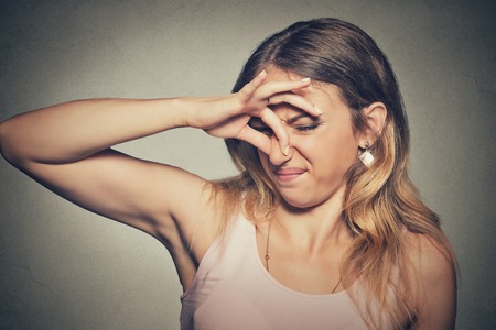 Closeup portrait headshot woman pinches nose with fingers hands looks with disgust something stinks bad smell situation isolated on gray wall background. Human face expression body language reactionの写真素材