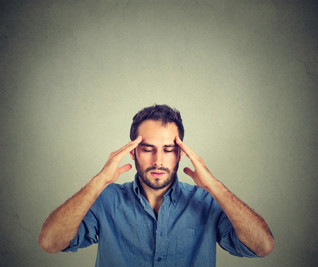 man thinking very intensely concentrating isolated on gray wall backgroundの写真素材