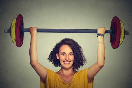 Happy strong young man lifting barbell above head with two handsの写真素材