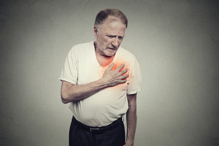 senior man suffering from bad pain in his chest heart attack isolated on gray backgroundの写真素材