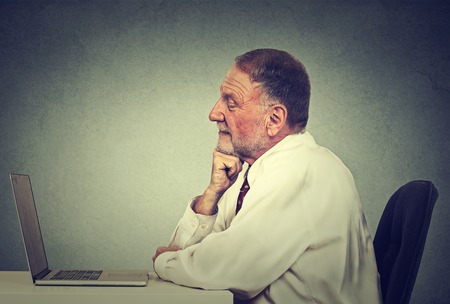 Senior man using laptop computer reading email news. E-learning conceptの写真素材