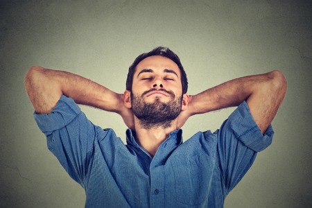 Closeup portrait of happy young man in blue shirt looking upwards in thought relaxing or napping isolated on gray wall backgroundの写真素材