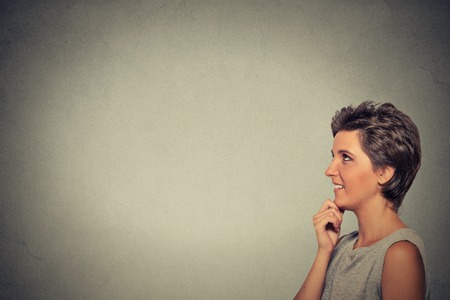 Side profile portrait happy beautiful woman thinking looking up isolated on grey wall background...