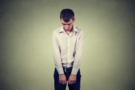 sad lonely young man looking down has no energy motivation in life depressed isolated on gray wall backgroundの写真素材