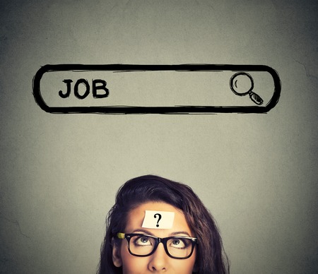 Headshot young woman in glasses thinking looking for a new job isolated on gray wall backgroundの写真素材