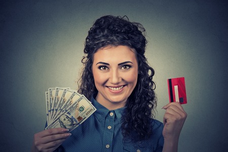Young woman shopping holding showing credit card and cash dollar banknotes bills