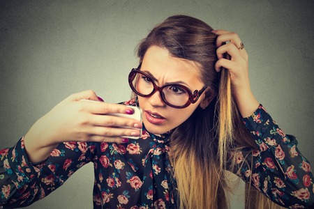 Closeup unhappy frustrated upset young woman surprised she is losing hair, receding hairline. Gray background. Human face expression emotion. Beauty hairstyle conceptの写真素材