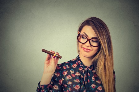 beautiful young woman with cigar isolated on gray wall backgroundの写真素材