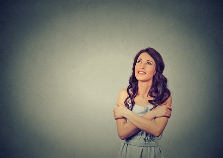 Closeup portrait confident smiling woman holding hugging herself dreaming contemplating isolated gray wall background. Positive human emotion facial expression feeling, attitude. Love yourself conceptの写真素材