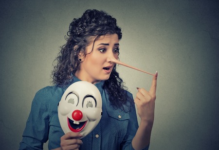 Woman with long nose and clown mask isolated on grey wall background. Liar concept. Human face expressions, emotions, feelings.の写真素材