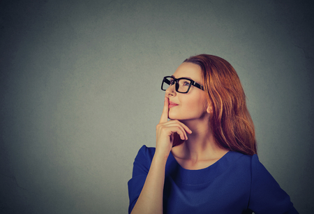 Portrait side profile happy beautiful woman thinking looking up isolated on grey wall background with copy space. Positive human face expressions, emotions, feelings, body language, perceptionの写真素材