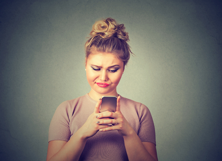 Closeup portrait upset sad skeptical unhappy serious woman talking texting on phone displeased with conversation isolated gray background. Negative human emotion face expression feeling reactionの写真素材