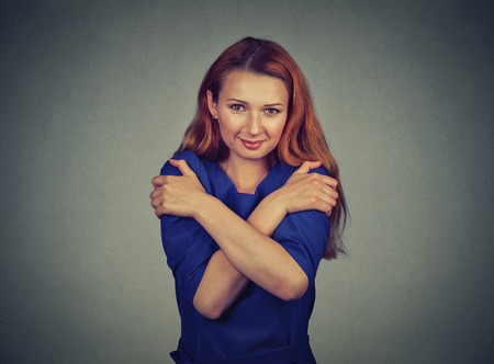 Closeup portrait confident smiling woman holding hugging herself isolated gray wall background....