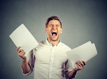 Angry stressed screaming business man with documents papers paperwork isolated on gray wall background. Negative emotions face expressionの写真素材
