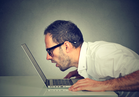Side profile man staring closely intensely at laptop screen