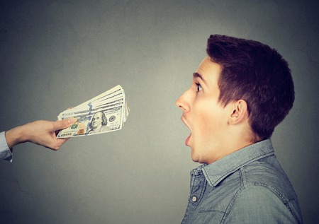 Shocked surprised man looking at offered cash dollar billsの写真素材
