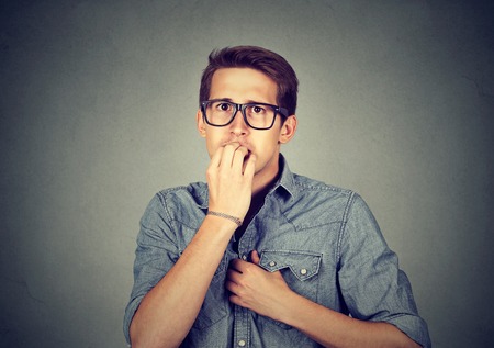 Preoccupied anxious young man biting fingernails nervouslyの写真素材