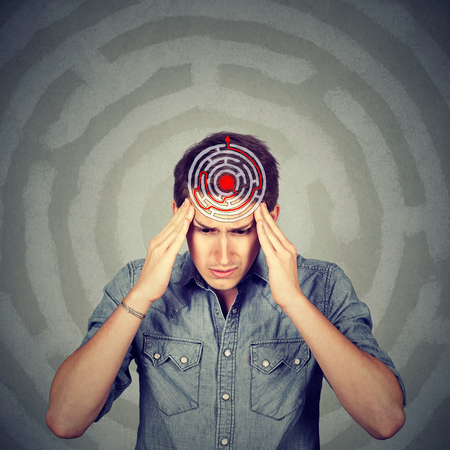 Problem solution concept. Young man solving puzzle isolated on gray wall background