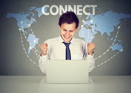 Modern communication technology web connection concept. Happy young man using laptop computer connected browsing internet worldwide world map on a background.の写真素材