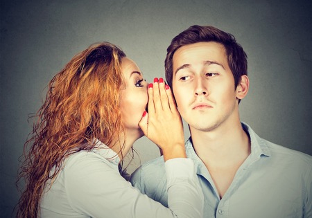 Speak in the ear. Young woman whispering to a handsome guyの写真素材