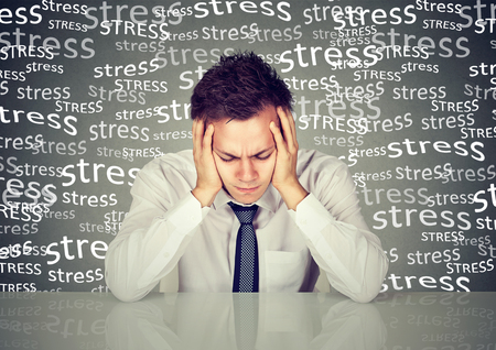 Desperate young business man leaning on a desk isolated grey wall background. Negative human emotions face expression feelings life perceptionの写真素材