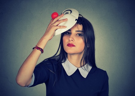 Young woman taking off a mask. Pretending to be someone else conceptの写真素材