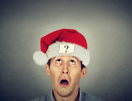 Young man in santa claus hat with question markの写真素材